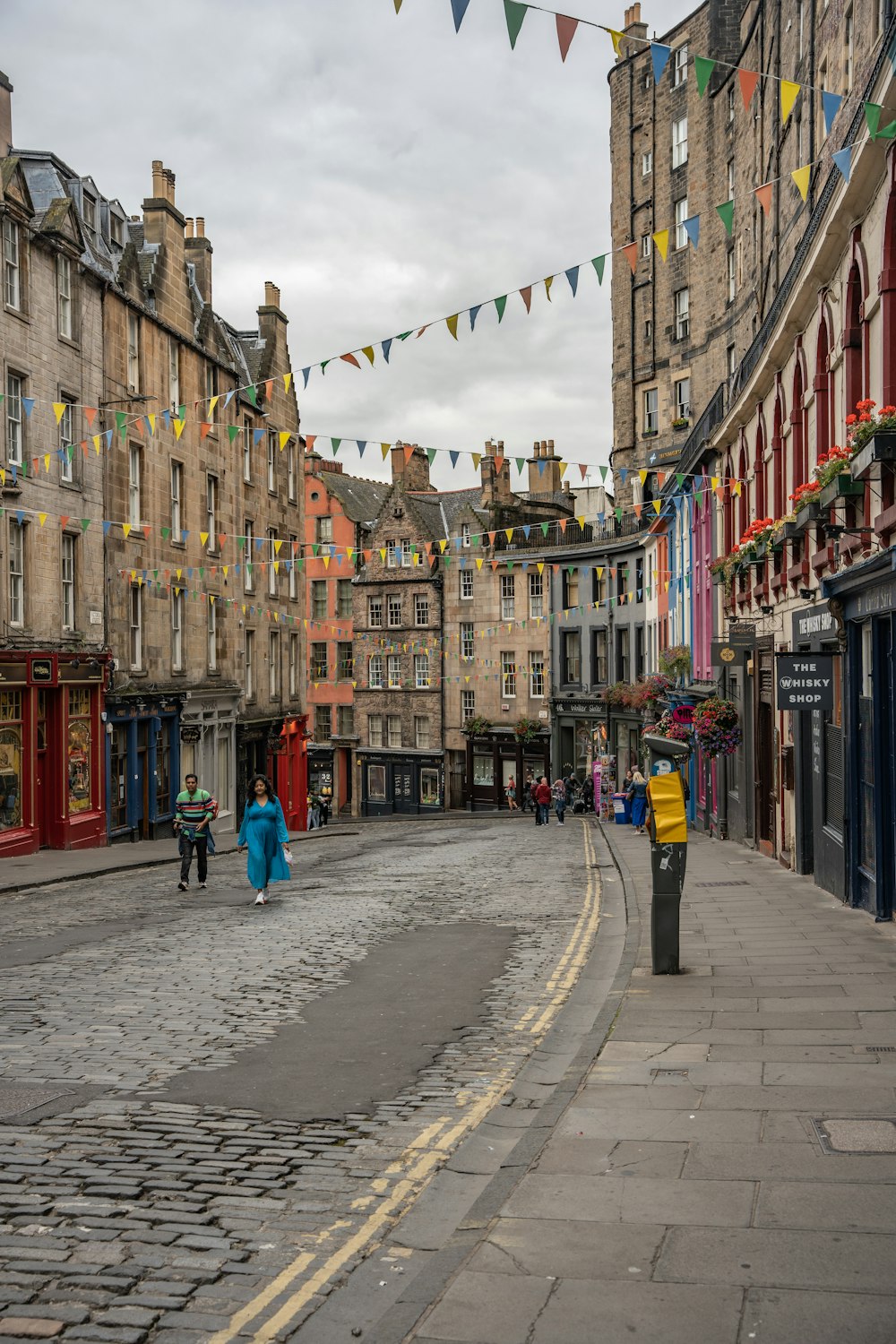 a cobblestone street lined with buildings and flags