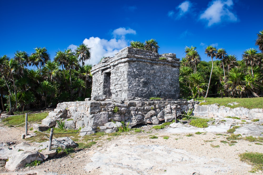 a stone structure with palm trees in the background