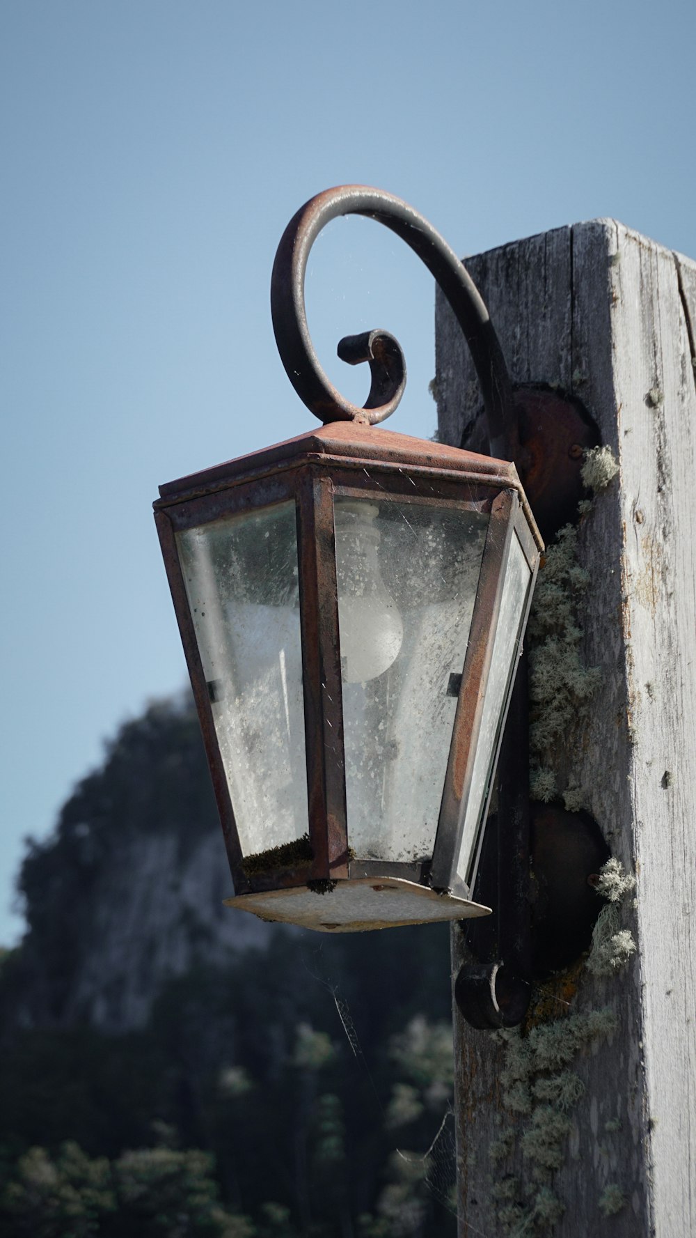 an old fashioned light hanging on a wooden post