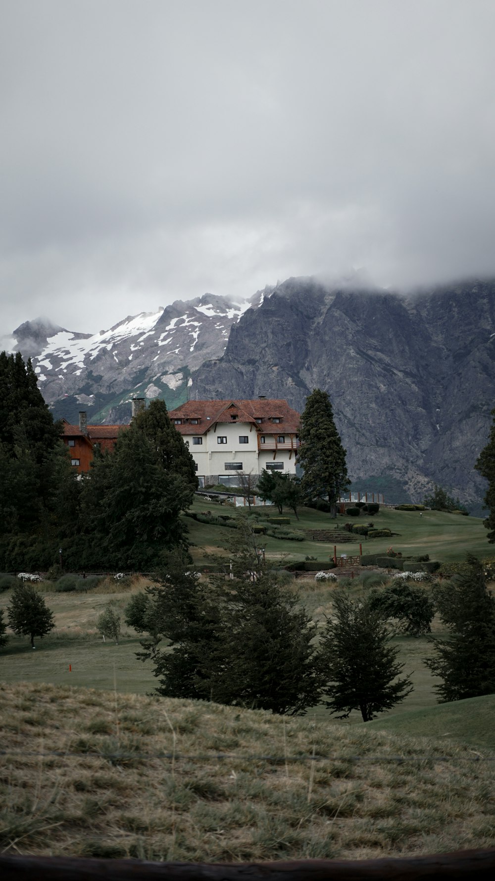 a house in the middle of a field with mountains in the background