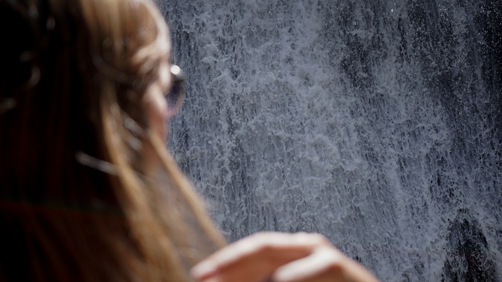 a woman standing in front of a waterfall