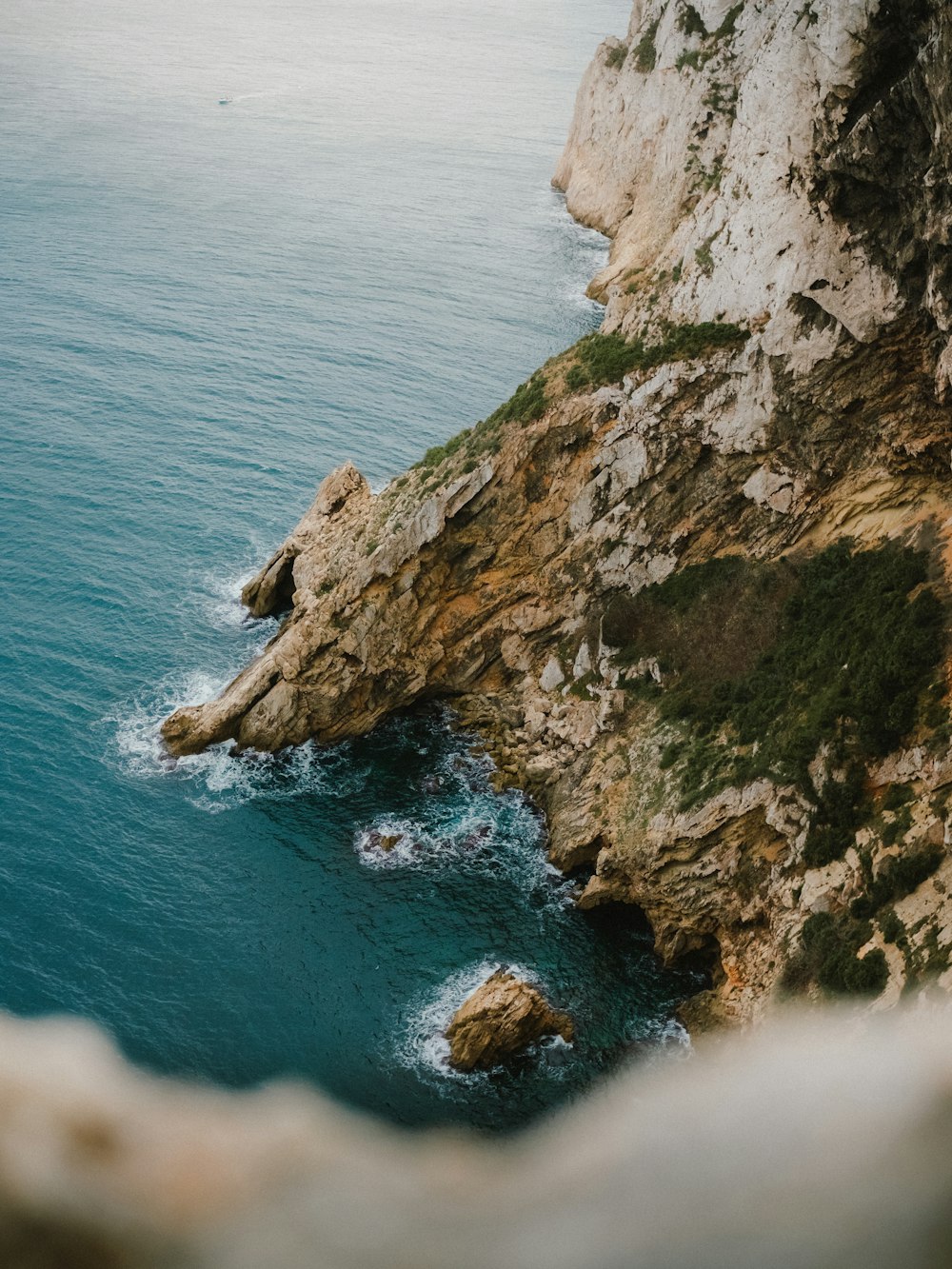 a couple of people standing on top of a cliff next to the ocean