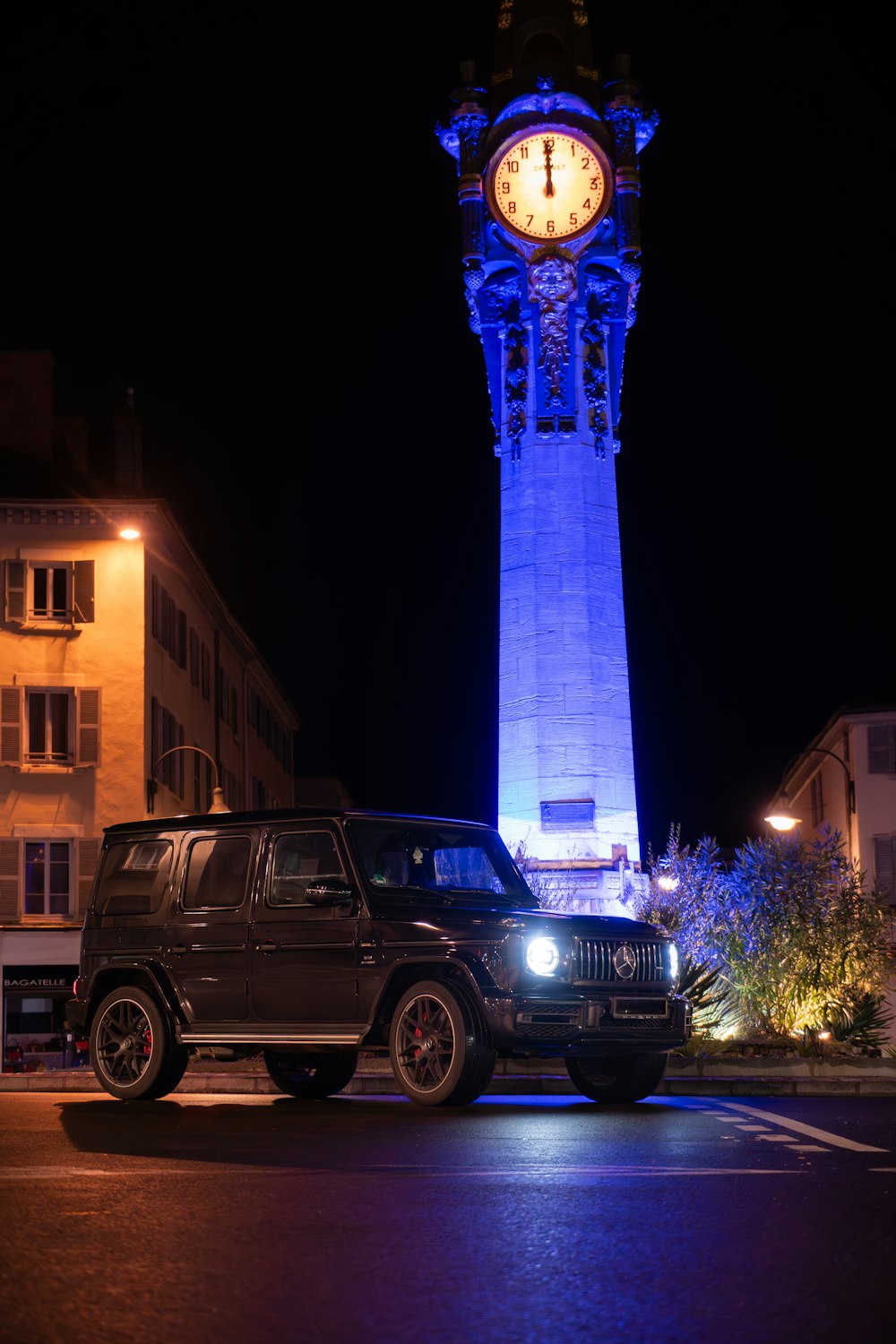 a car parked in front of a tall clock tower