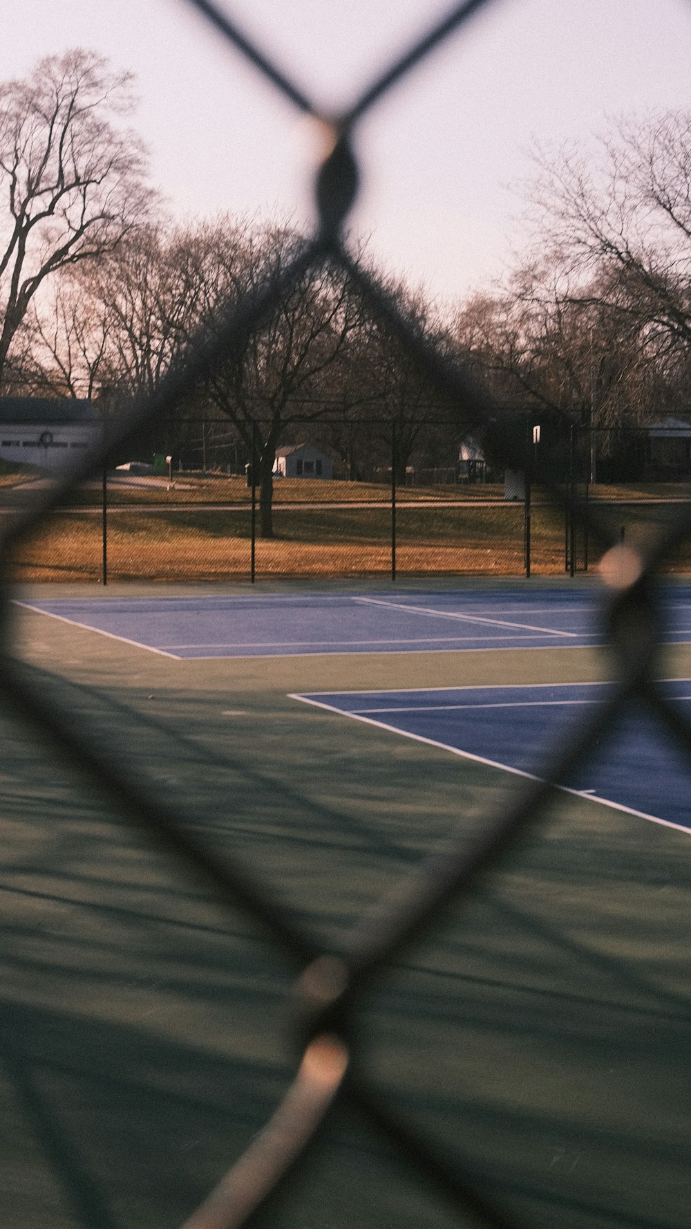 a tennis court seen through a chain link fence