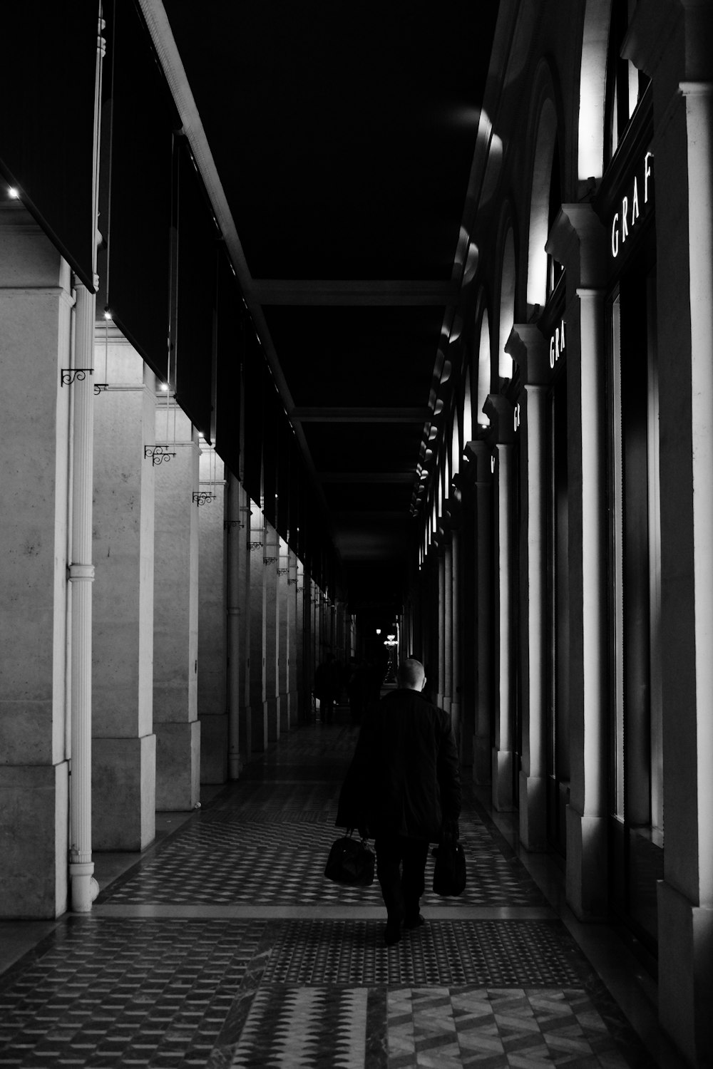 a black and white photo of a person walking down a hallway