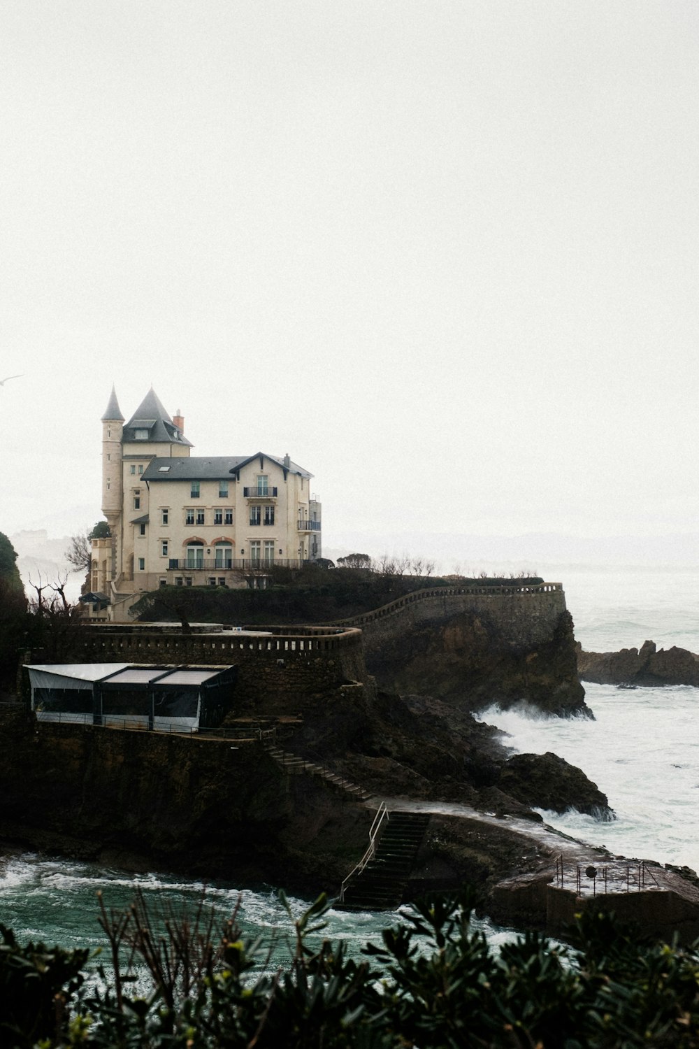 uma grande casa branca sentada no topo de um penhasco ao lado do oceano