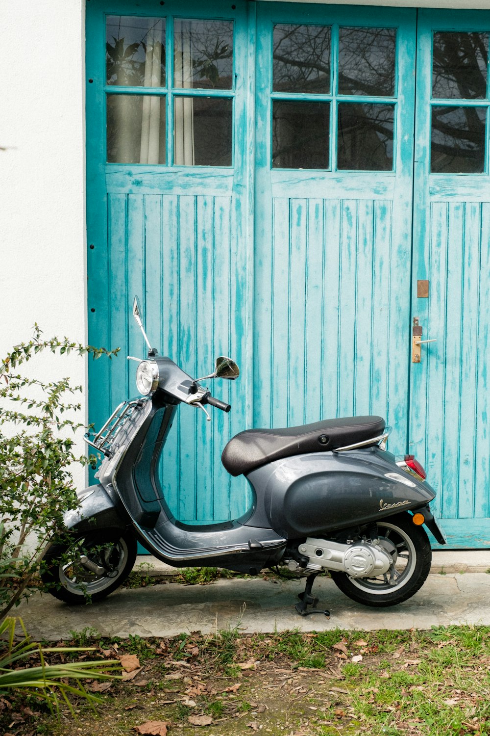un scooter garé devant une porte bleue