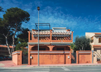 a red building with a balcony next to a street
