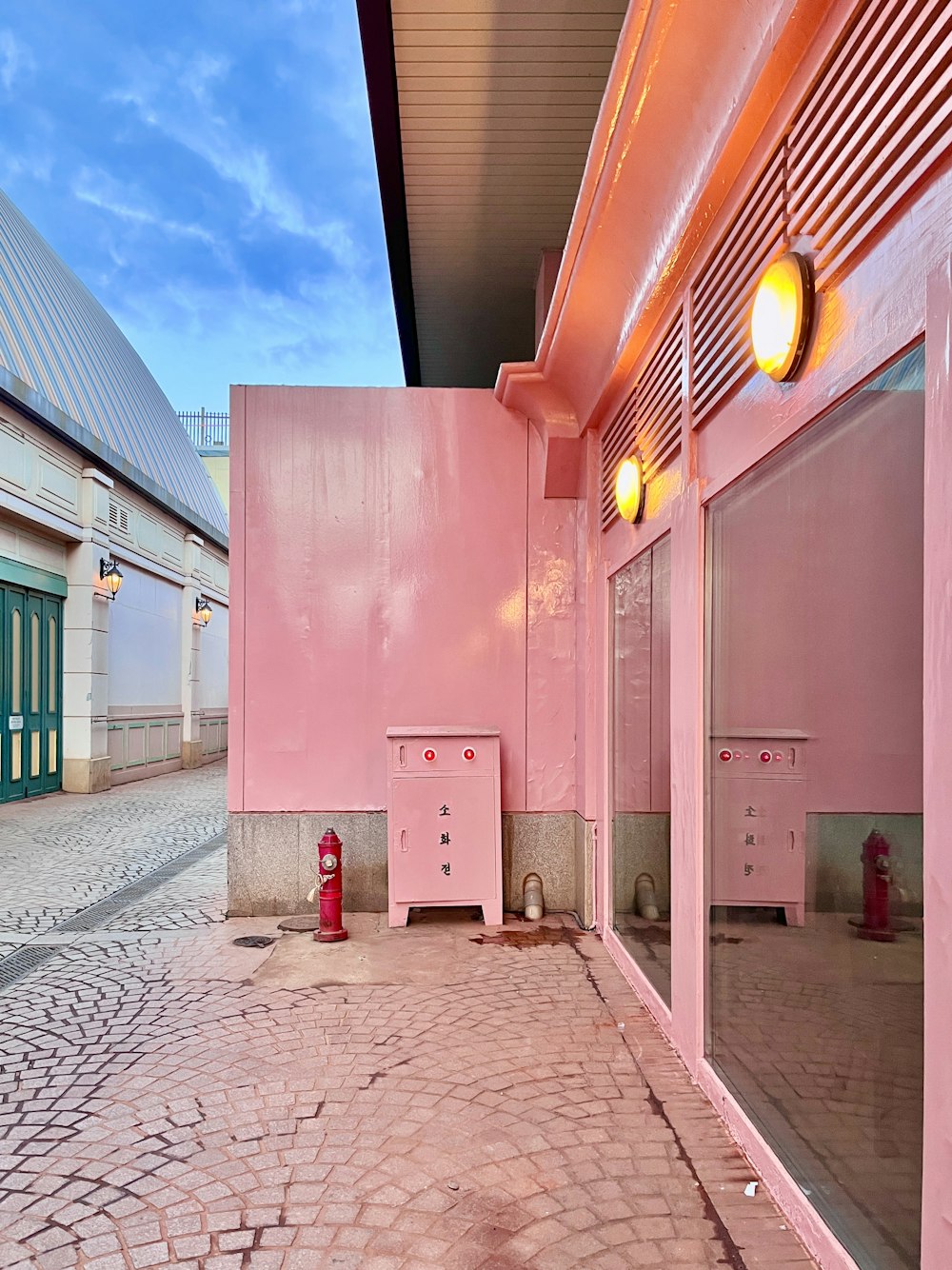 a red fire hydrant sitting next to a pink building