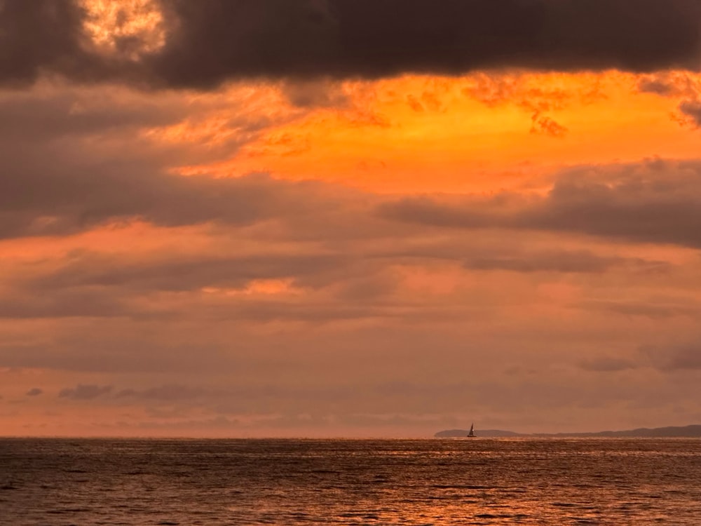 a sailboat is out on the ocean at sunset