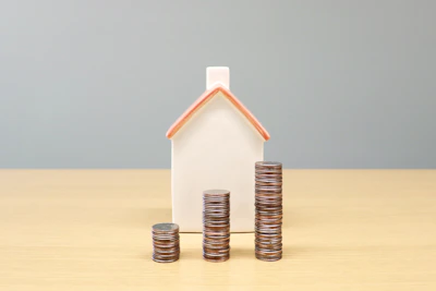 a house and stacks of coins on a table
