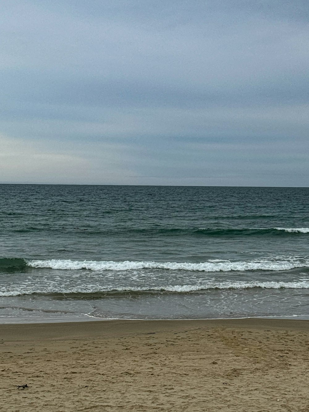 a person walking on the beach carrying a surfboard