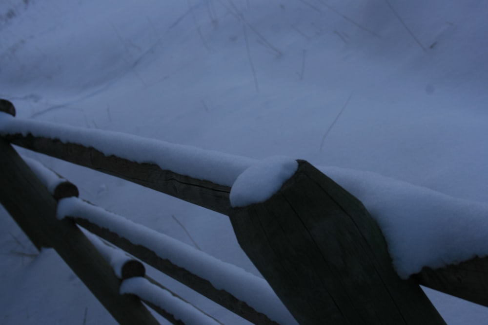 a wooden bench covered in snow on a snowy day