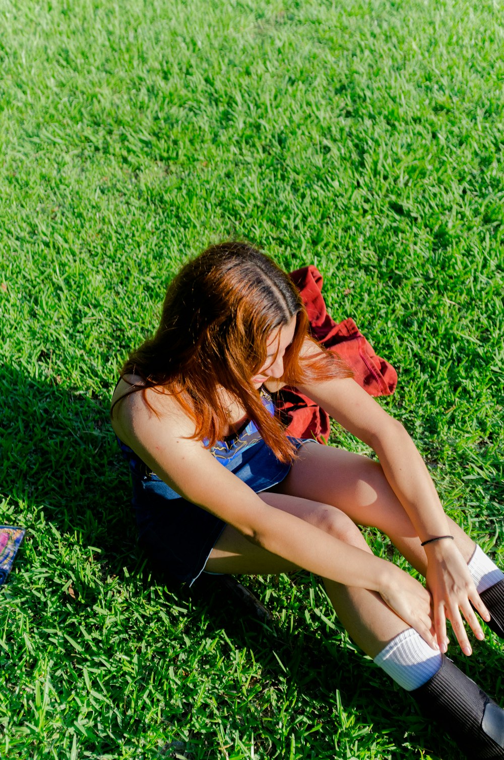 a woman sitting on the grass with her legs crossed