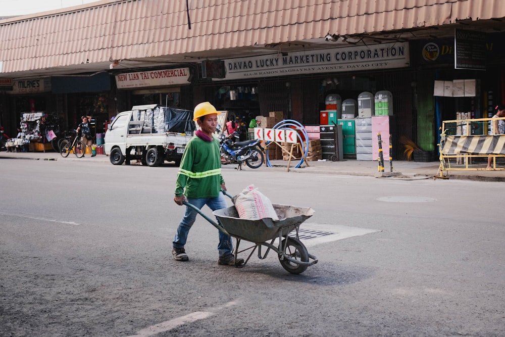 um homem empurrando um carrinho de mão por uma rua