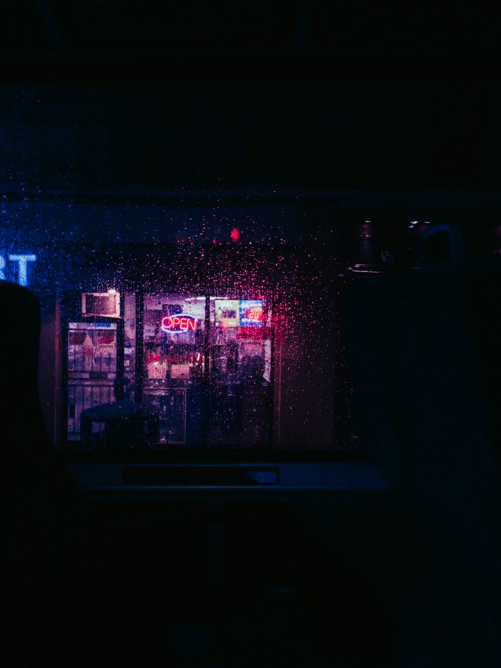 a dark room with a neon sign and a window