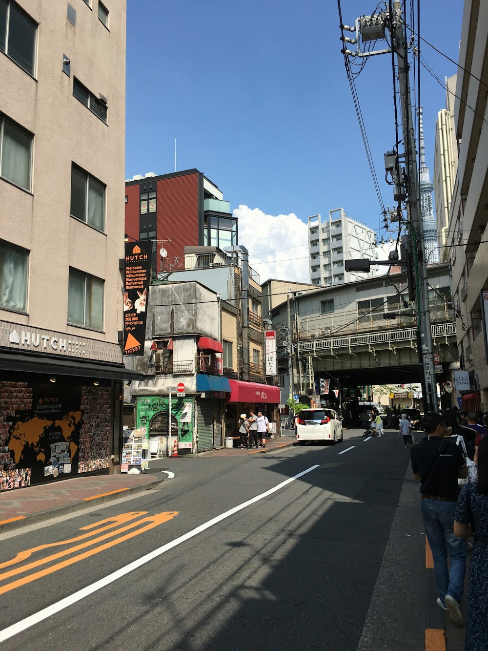 a group of people walking down a street next to tall buildings