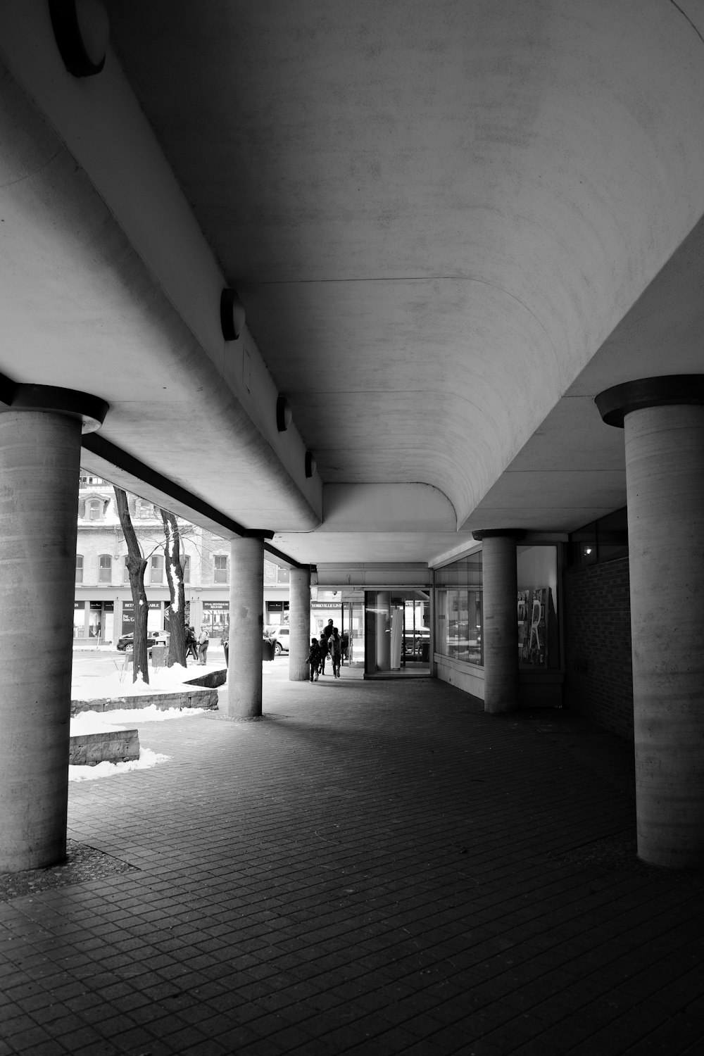 a black and white photo of people walking under a bridge