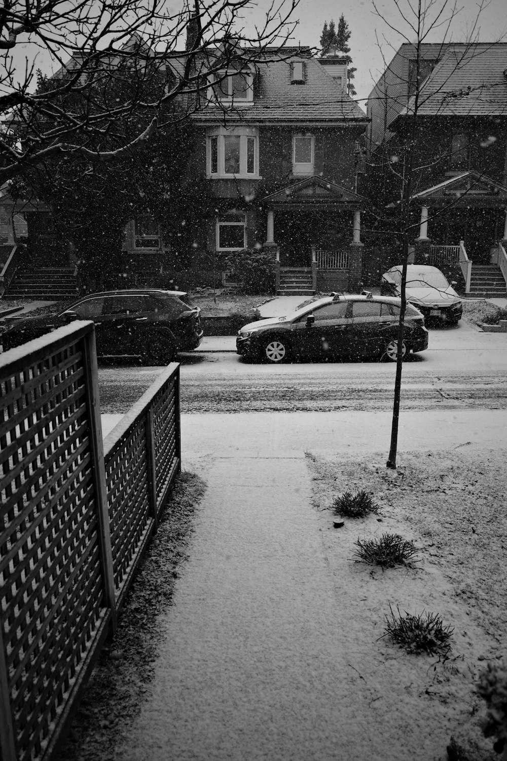 a black and white photo of a snow covered sidewalk