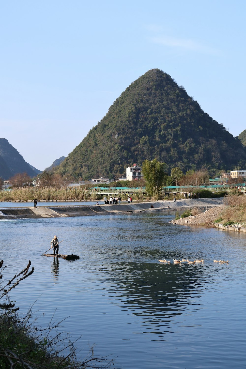 a man standing in a river next to a mountain