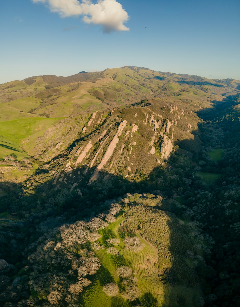 an aerial view of a mountain range with a cloud in the sky