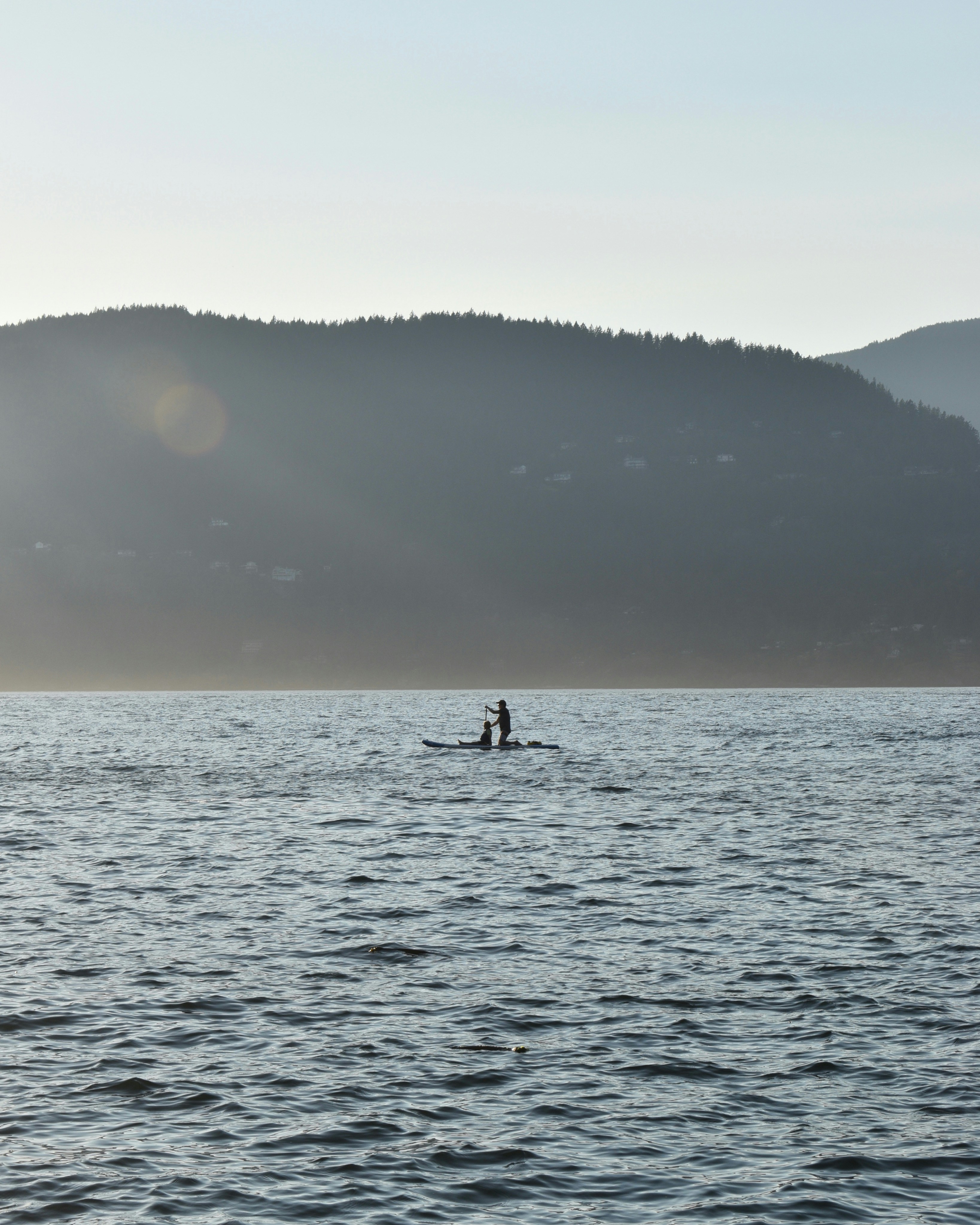 A person paddleboarding past a scenic coastline