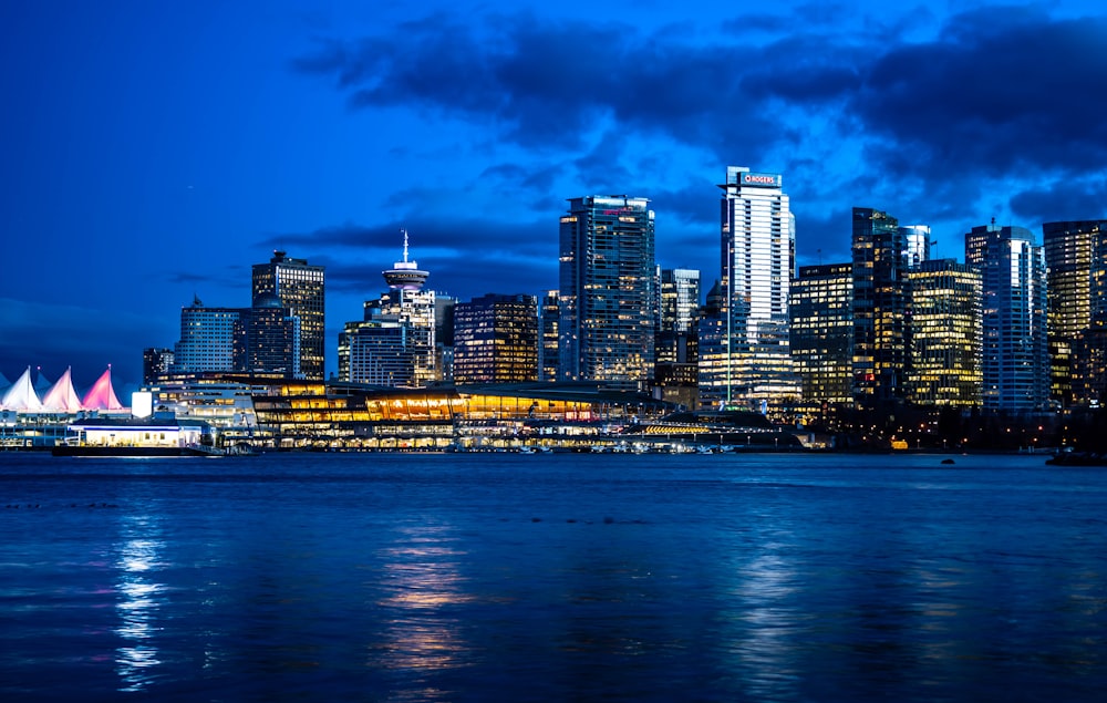 a city skyline at night with lights reflecting off the water