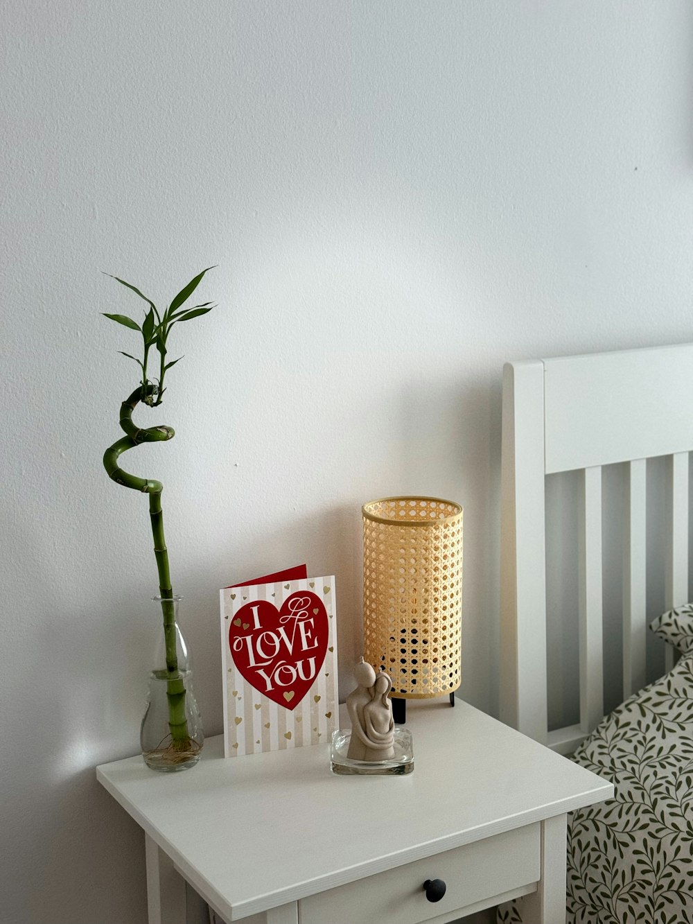 a small white table with a card and a plant on it
