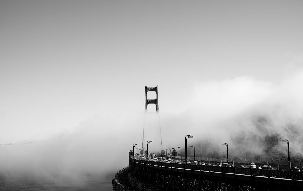 a black and white photo of a bridge in the fog