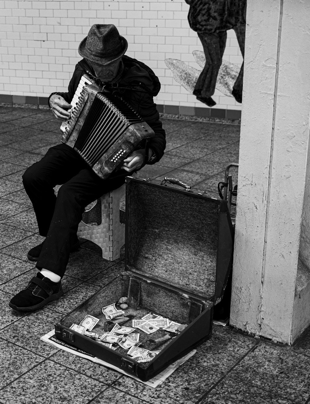 a man sitting on a suitcase playing an accordion