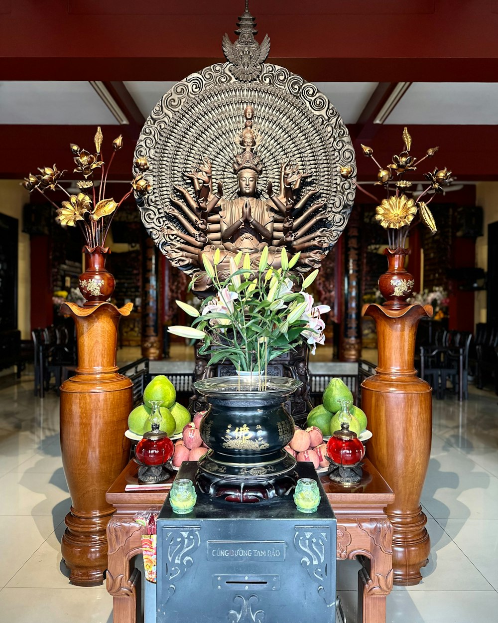 a statue of a buddha surrounded by vases and fruit