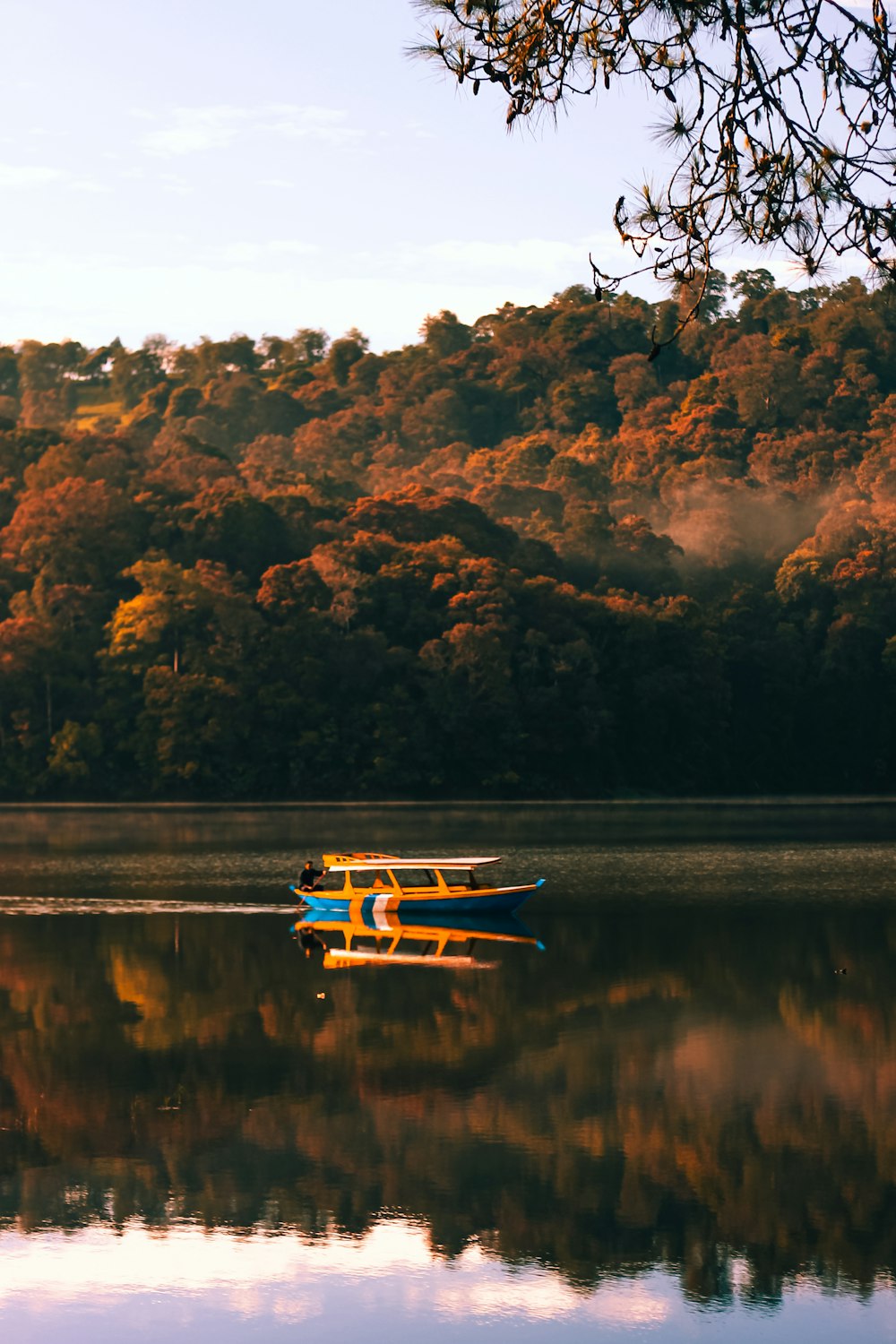 a yellow and blue boat floating on top of a lake