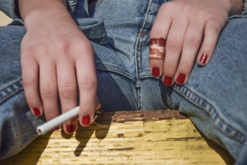 a woman sitting on a wooden bench with a cigarette in her hand