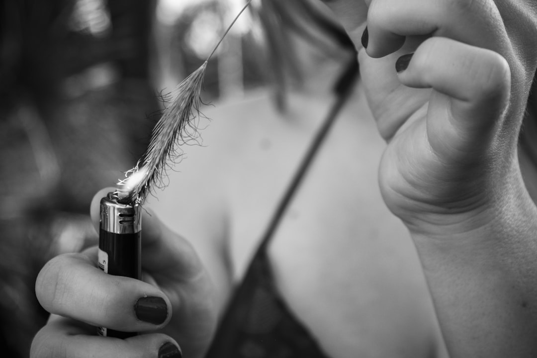 a woman holding a lighter with a feather on it,