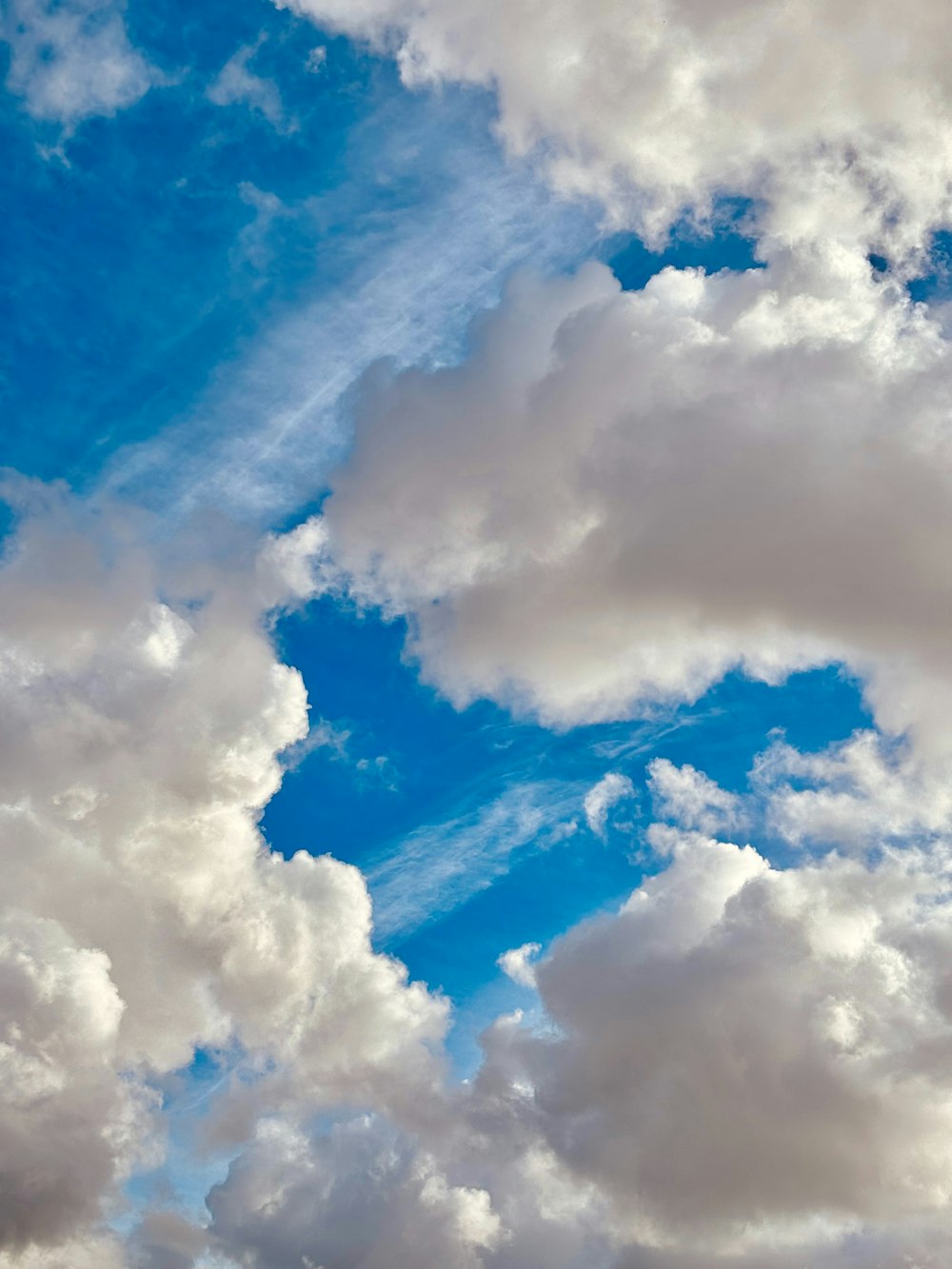 a plane flying through a cloudy blue sky