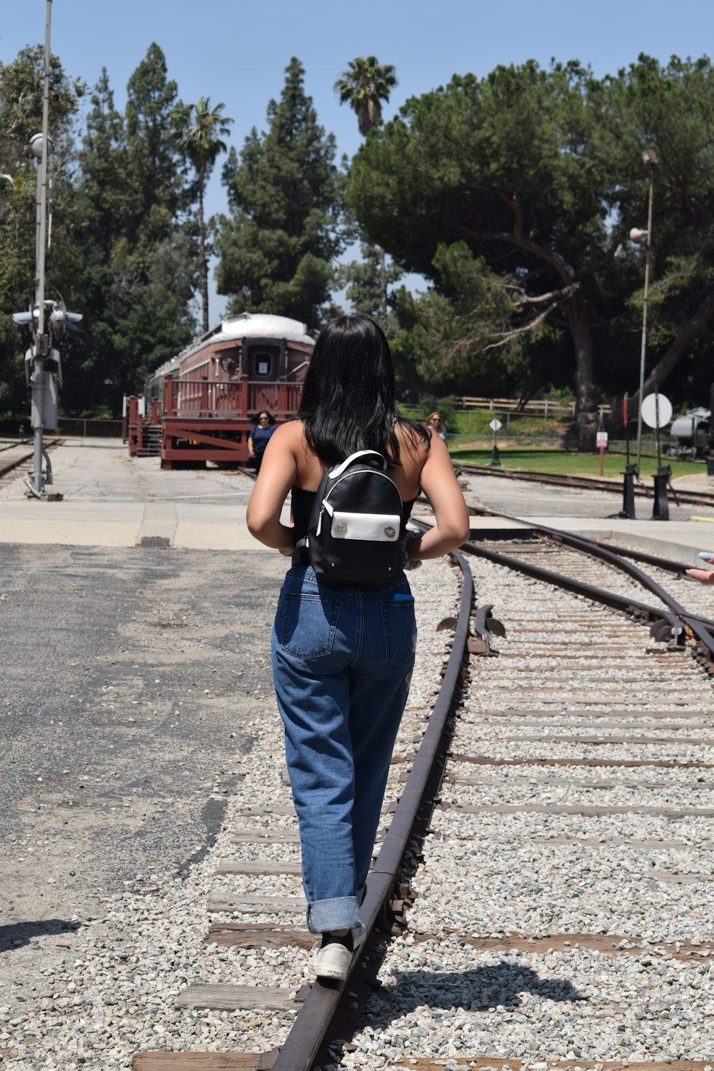 a woman walking down a train track with a backpack on her back