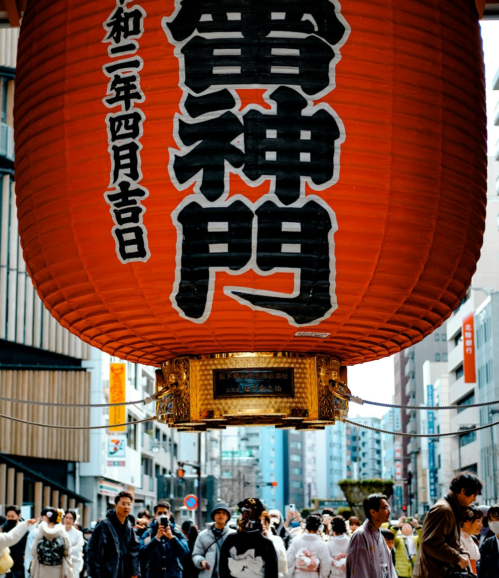 a group of people walking down a street under a red lantern