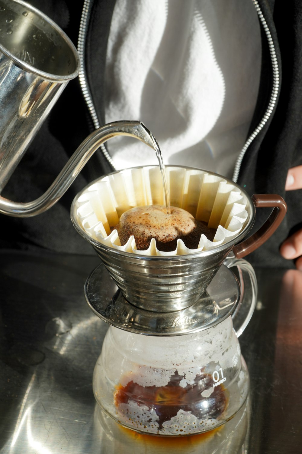 a person pours coffee into a glass pitcher