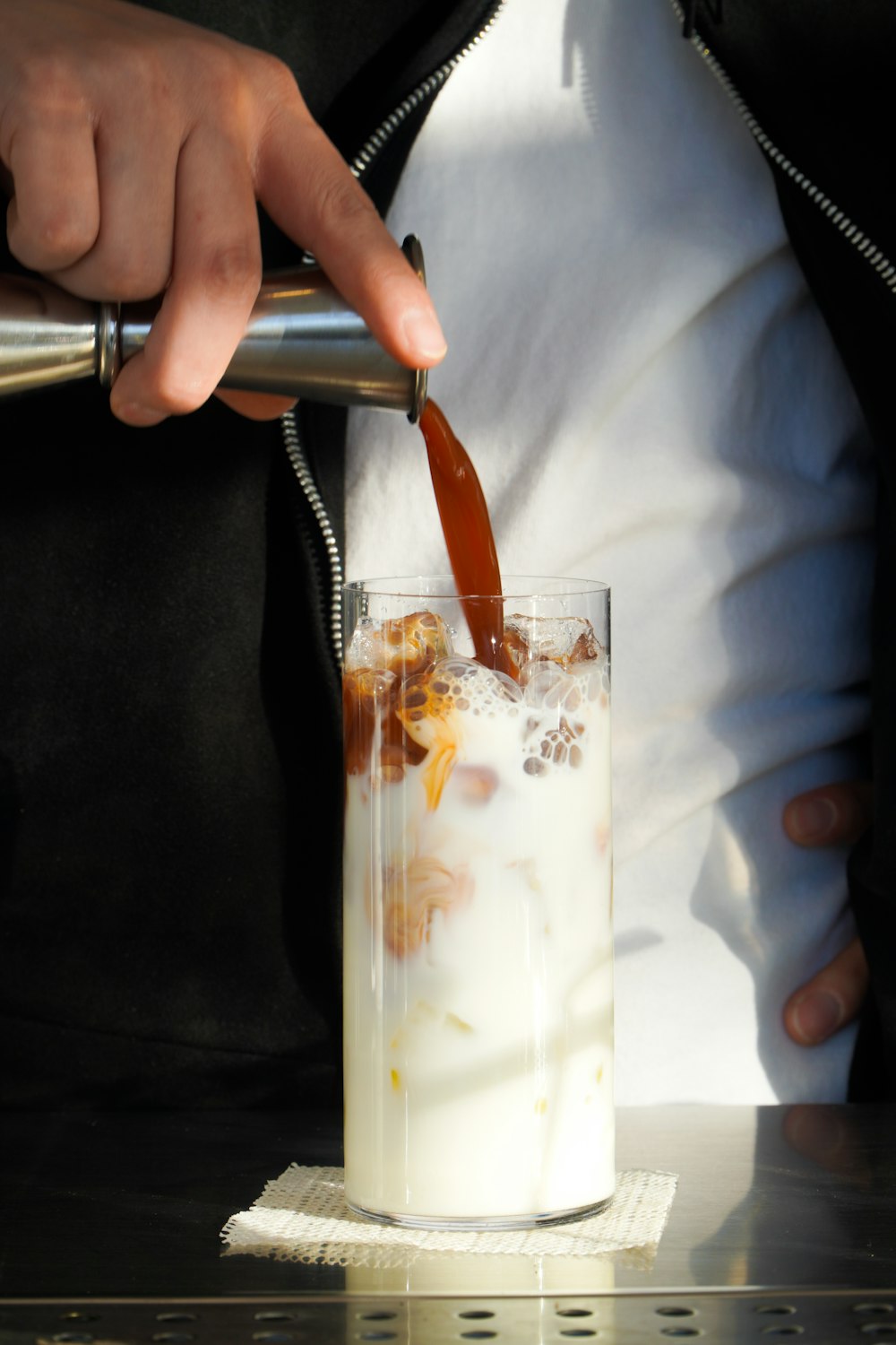 a person pouring a drink into a glass