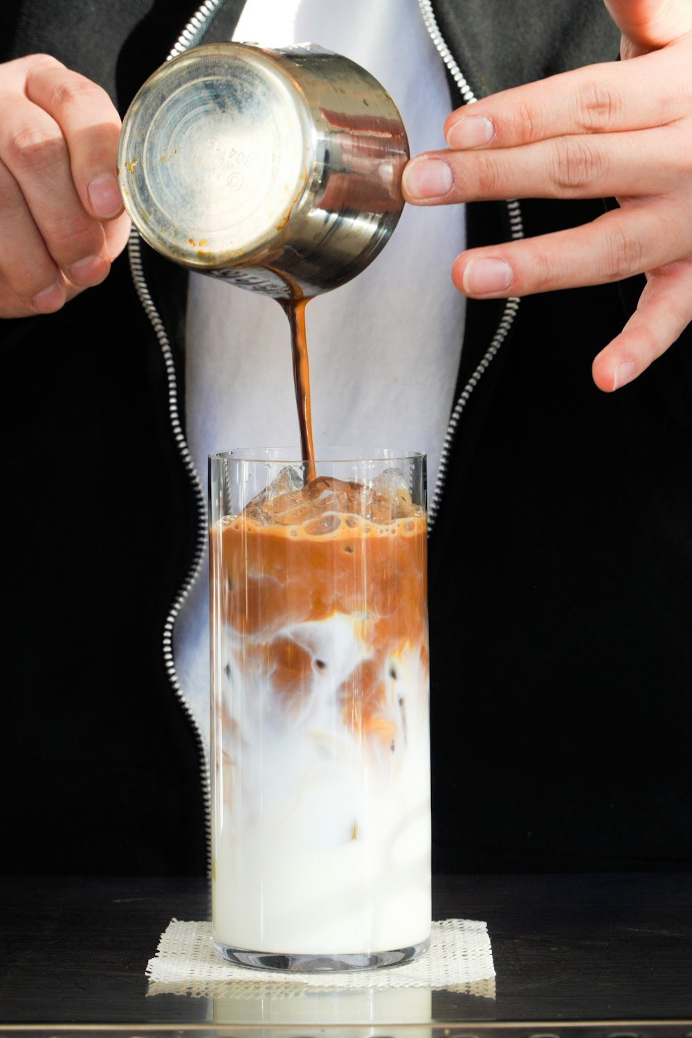 a person pouring a drink into a glass