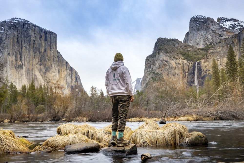 a man standing on a rock in the middle of a river