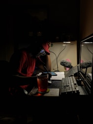 a man sitting in front of a computer in the dark