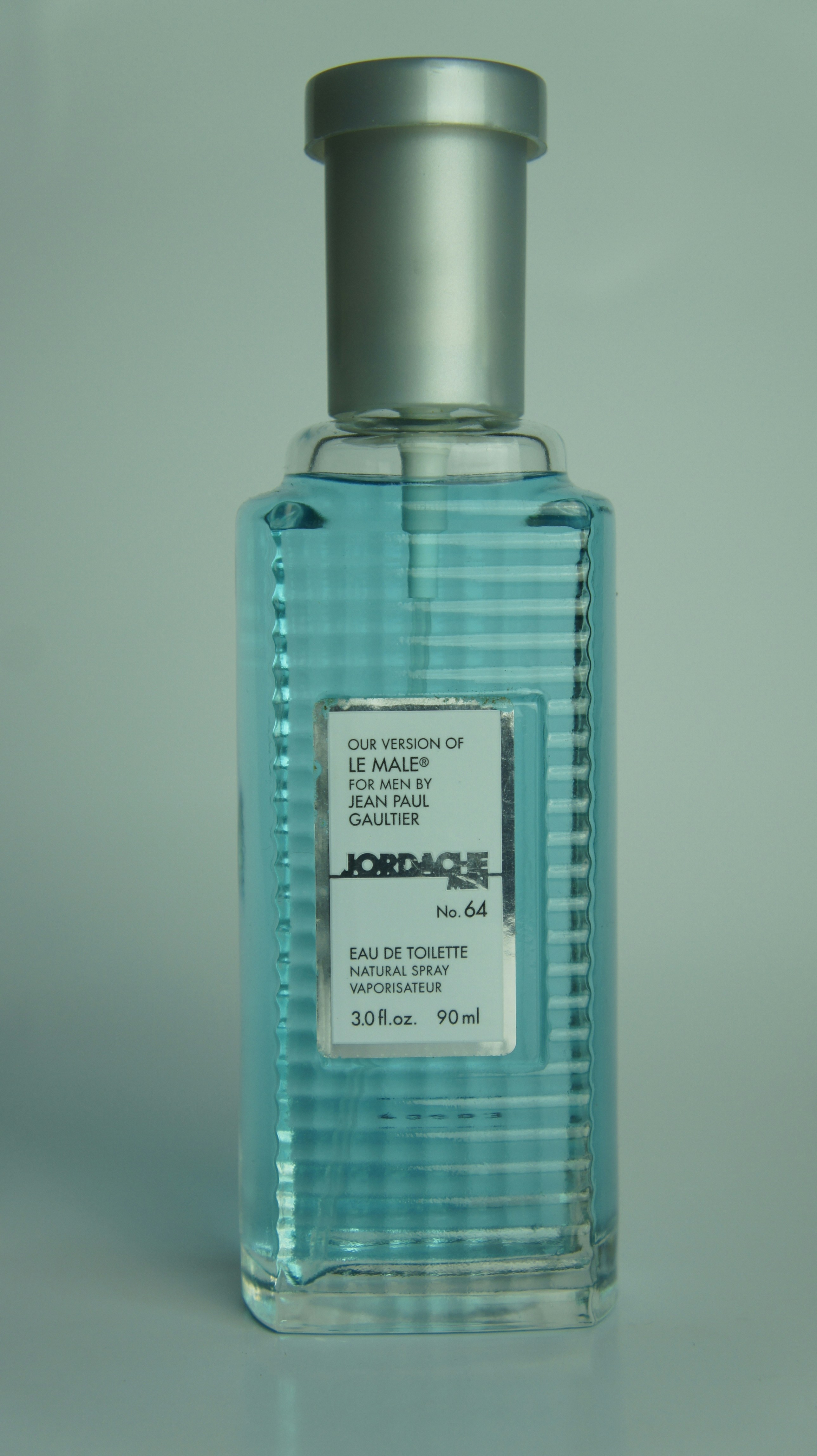 بطری عطر آبی رنگ با درپوش نقره‌ای روی پس‌زمینه آبی روشن