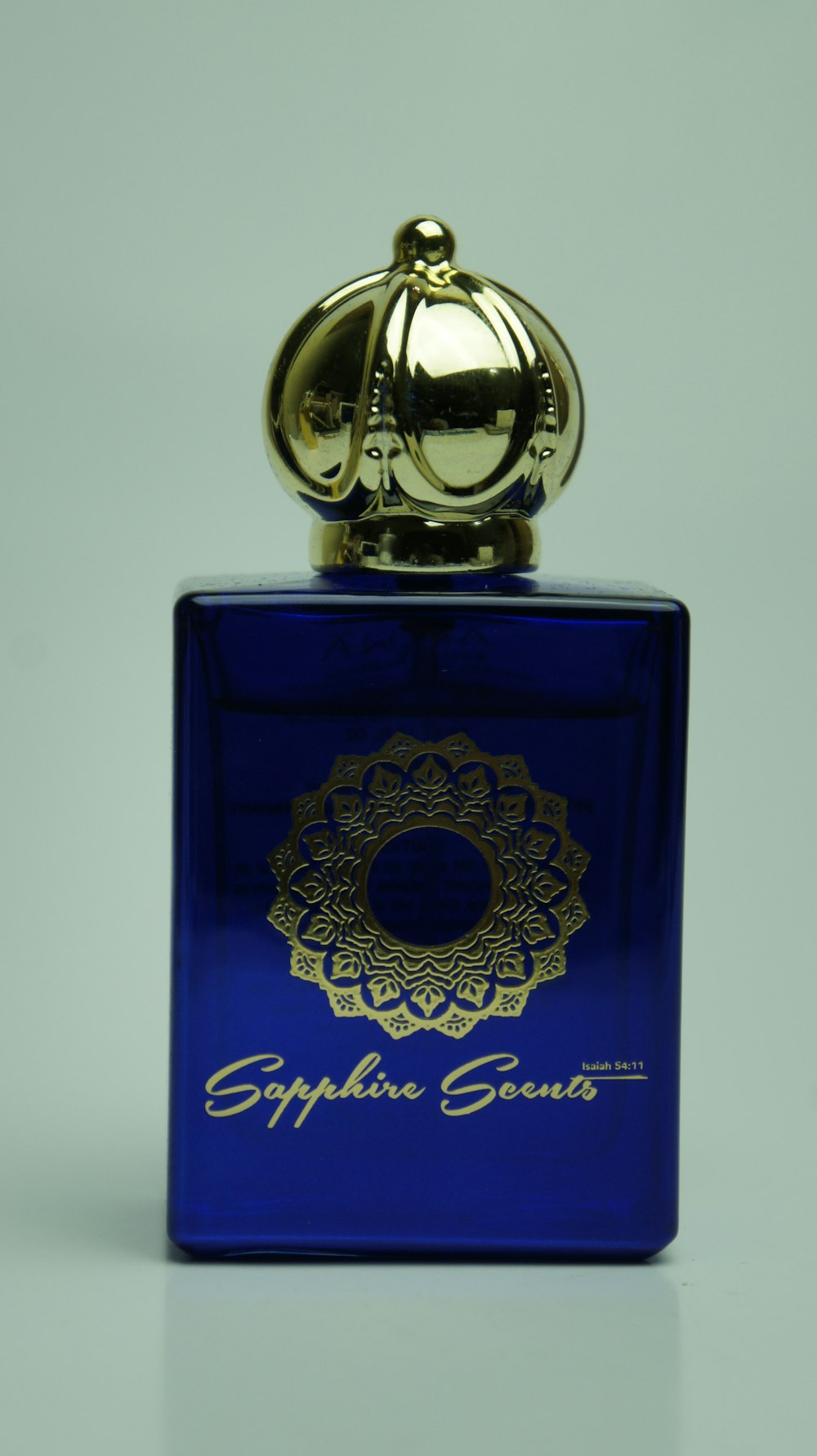 a blue bottle with a gold top on a white surface