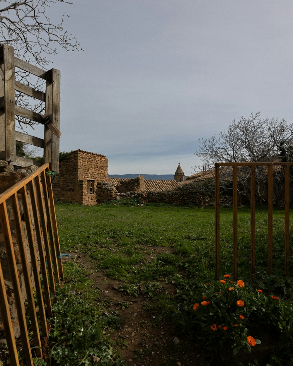 a wooden gate in the middle of a grassy field