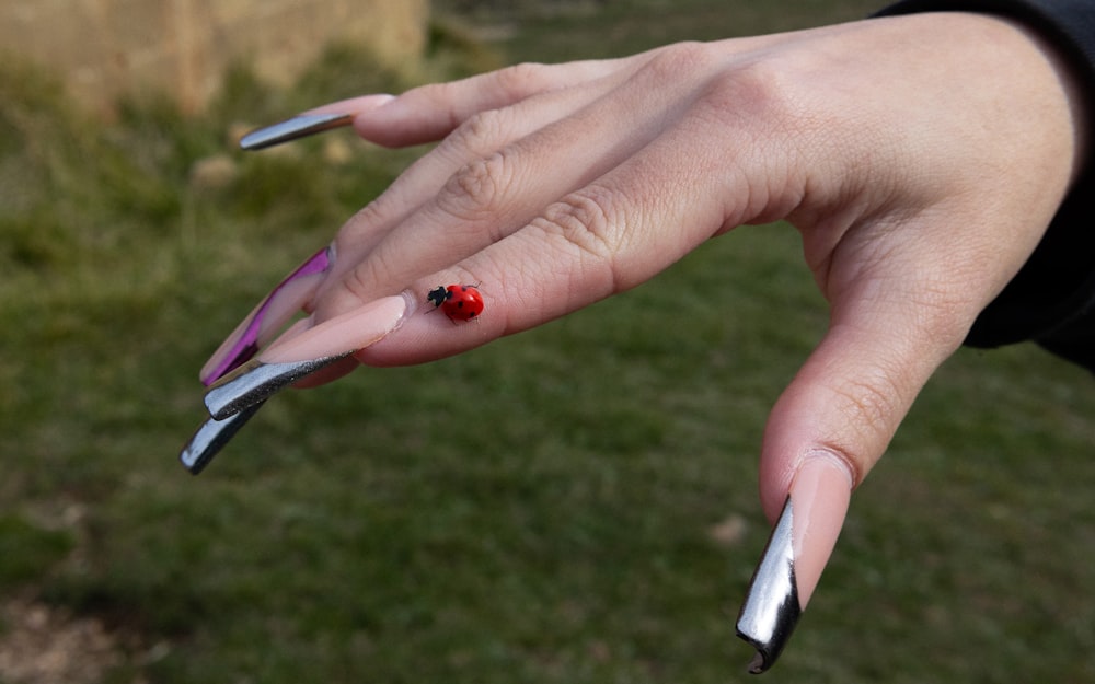 a woman's hand with silver and red nails