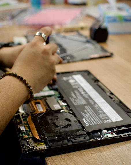 a person using a cell phone to repair a laptop