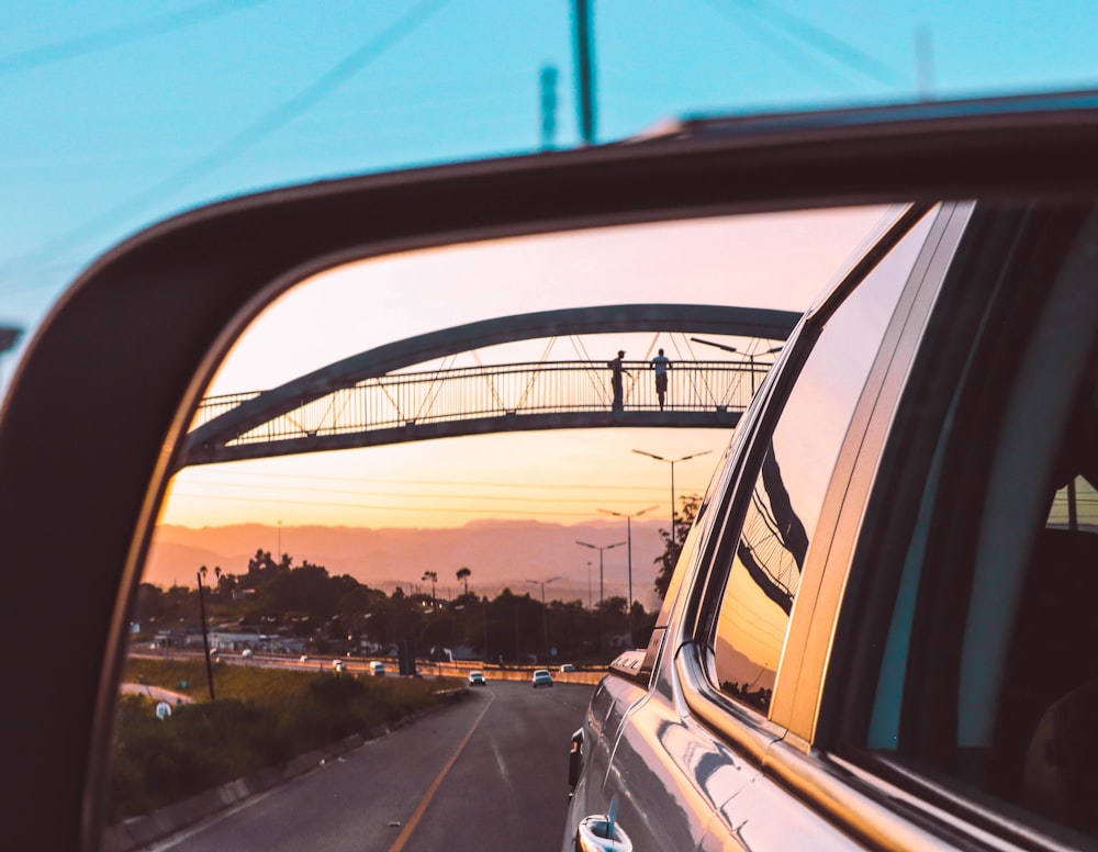 a car's rear view mirror with a bridge in the background