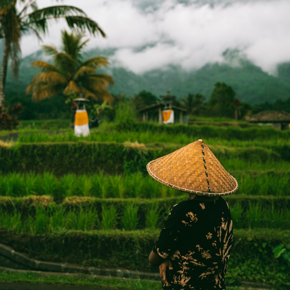 a woman wearing a straw hat walking down a road