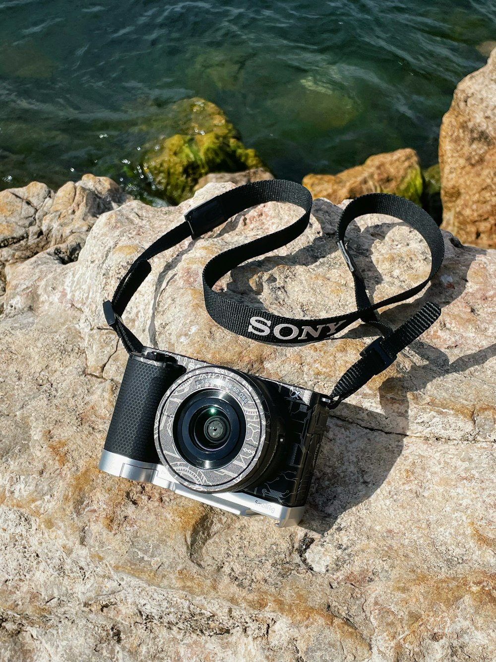 a camera sitting on top of a rock next to a body of water